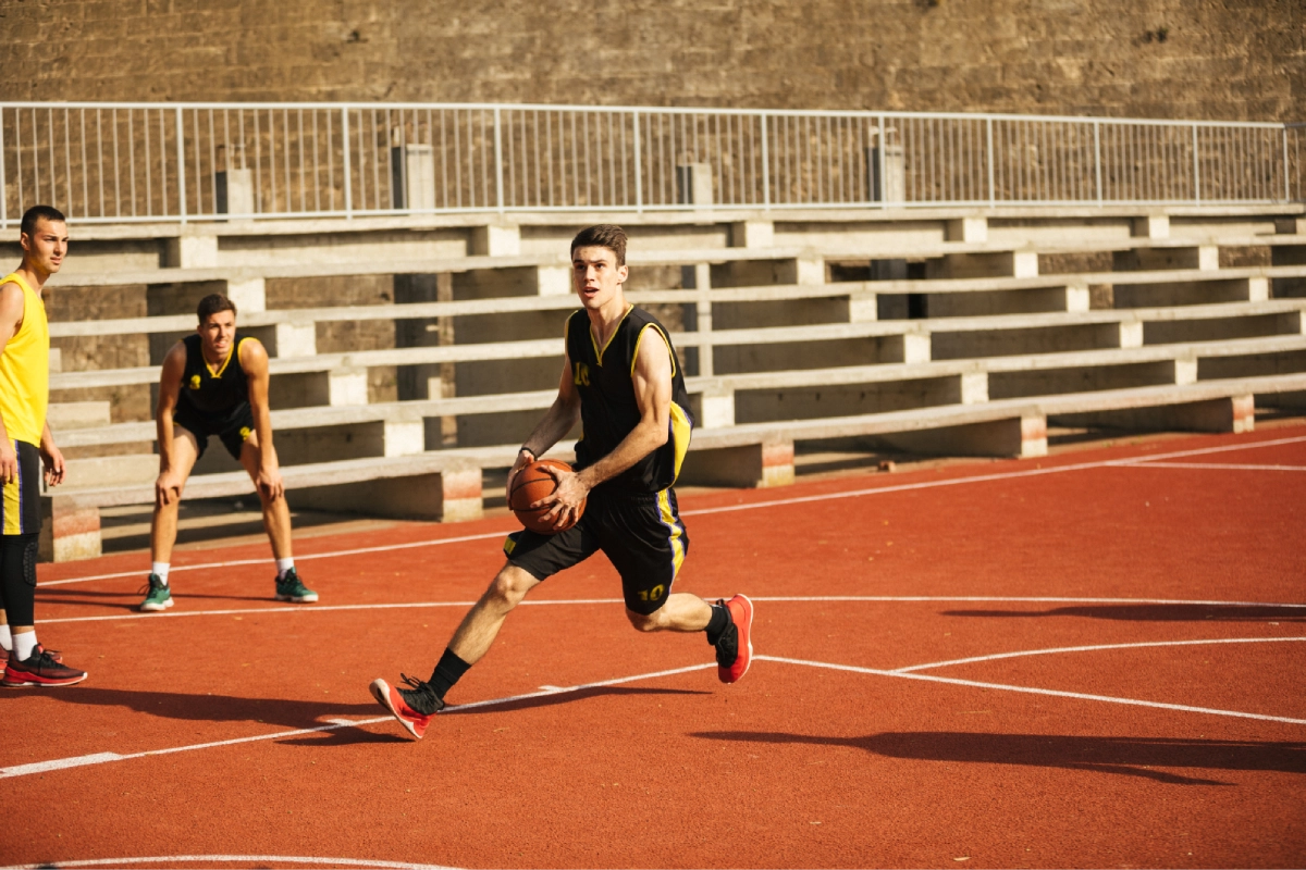 Basketball player dribbling on outdoor court
